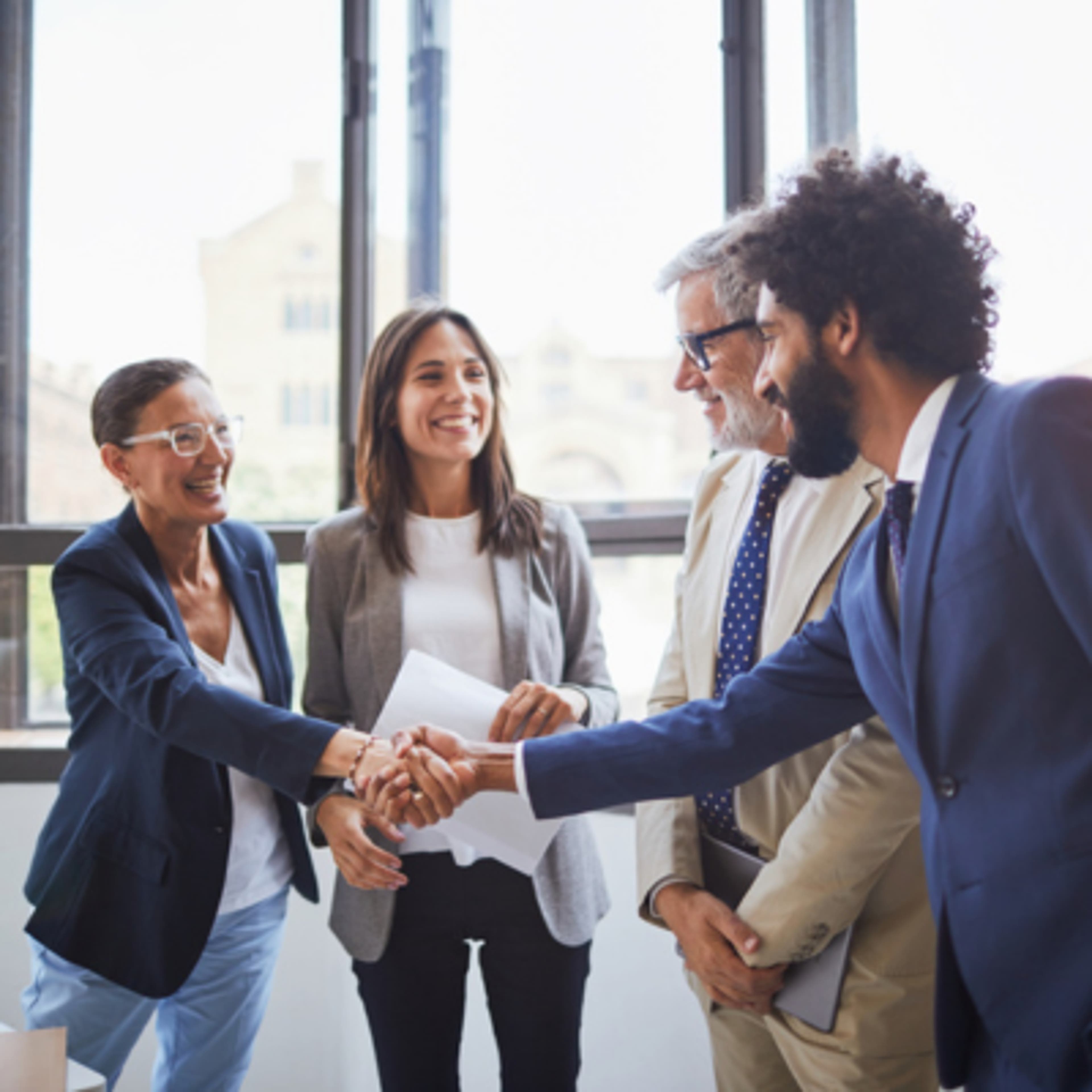 4 people talking to each other and one man shaking hand with a woman