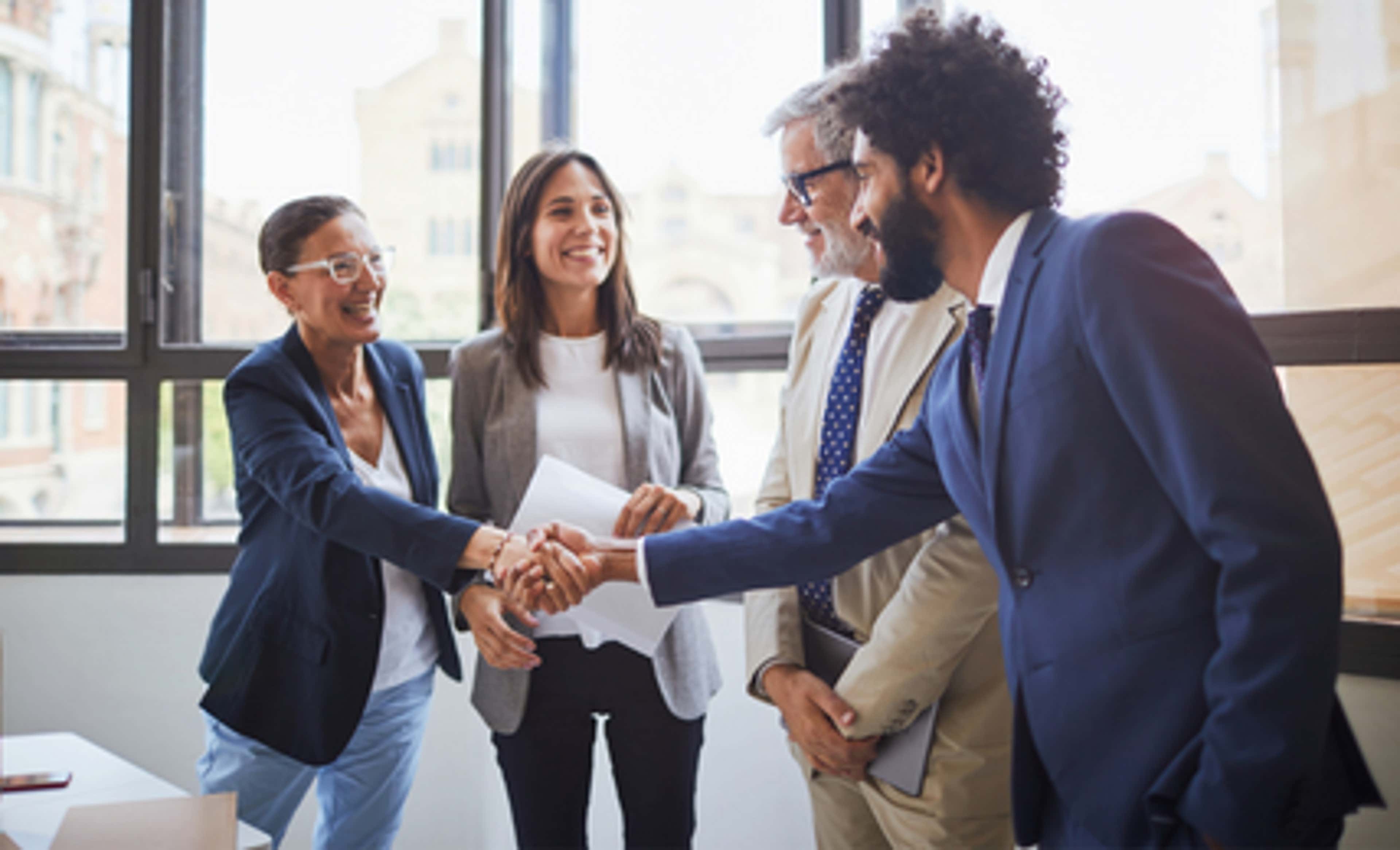 4 people talking to each other and one man shaking hand with a woman