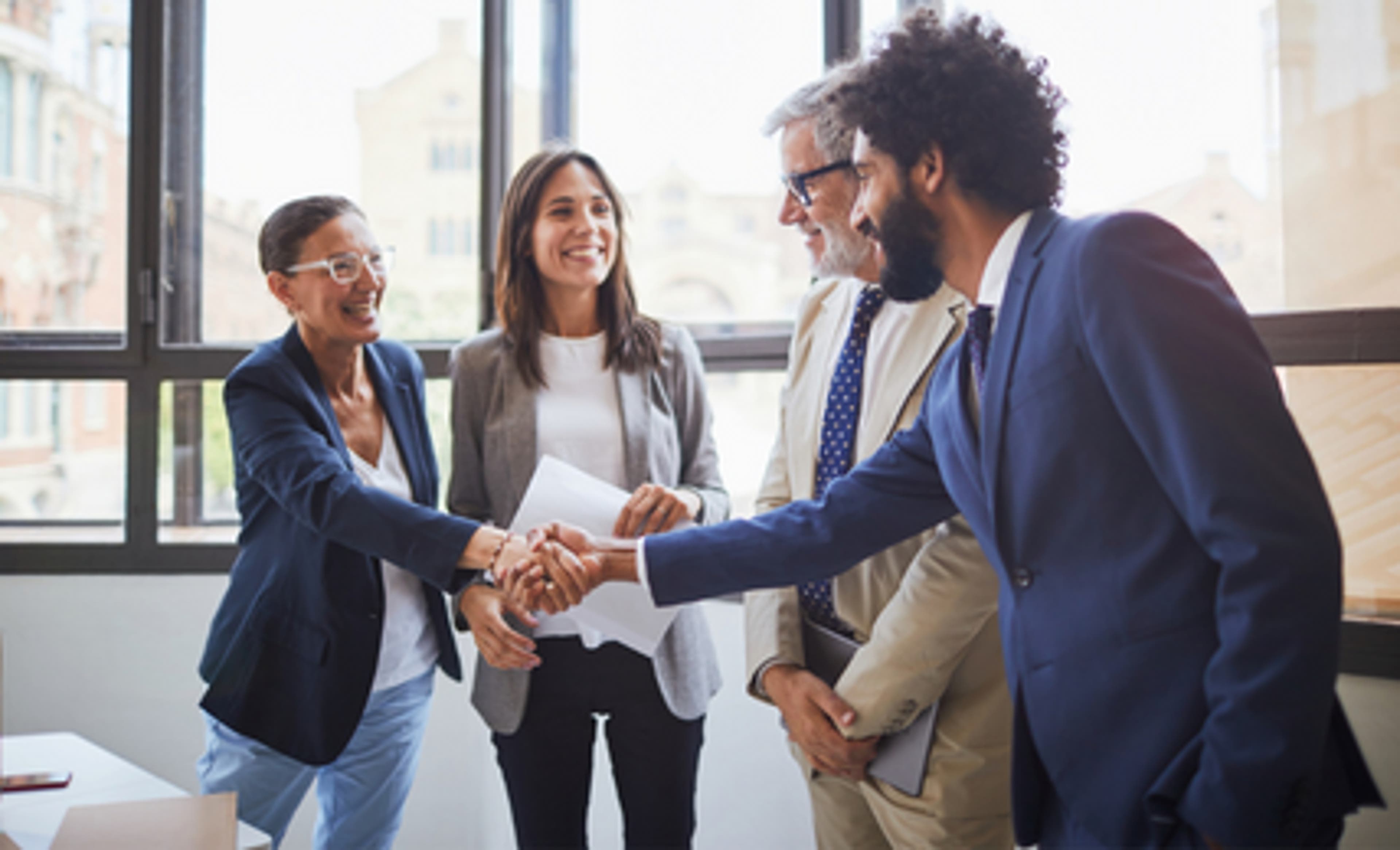 4 people talking to each other and one man shaking hand with a woman