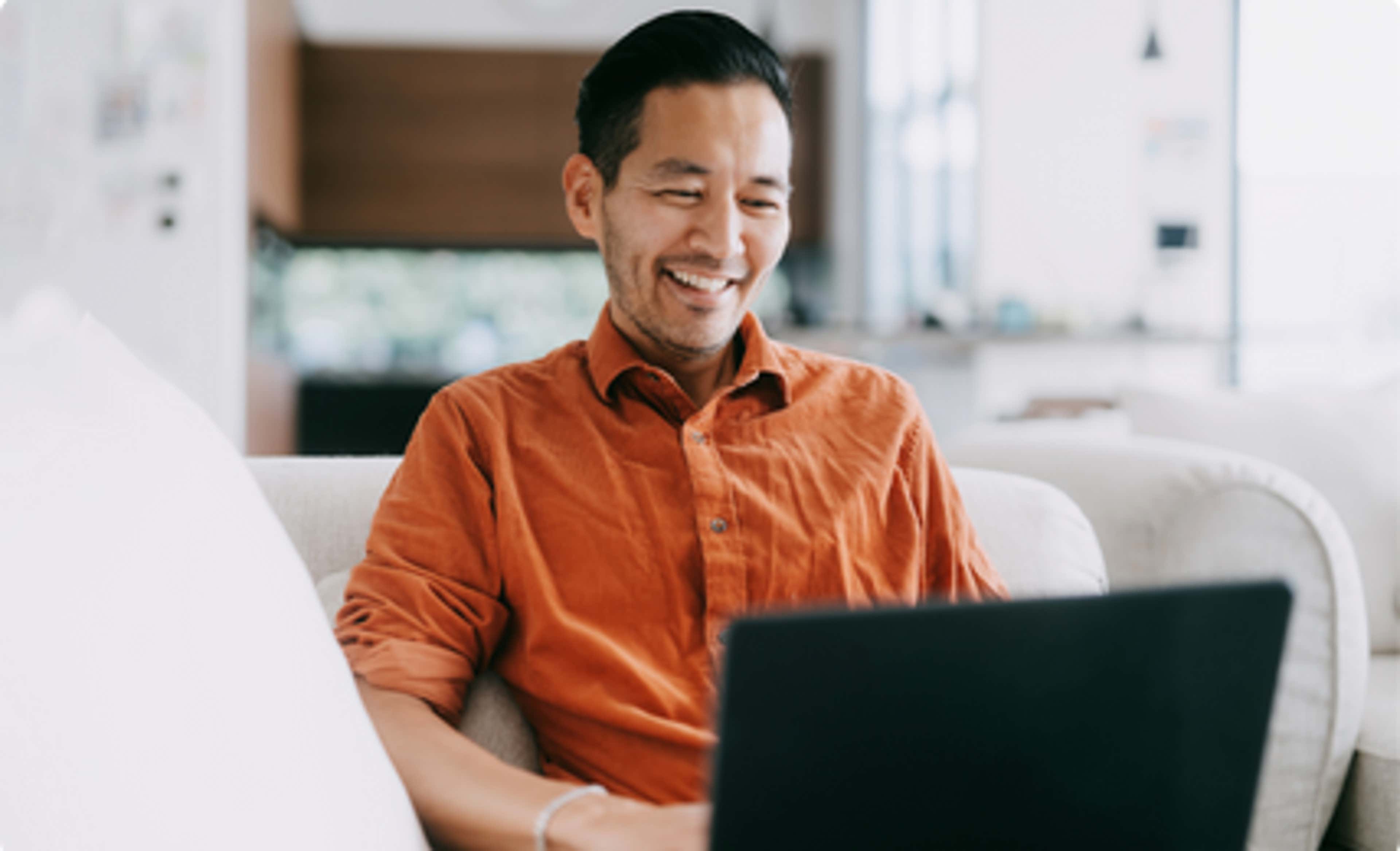 A man sitting with Laptop in Orange Shirt