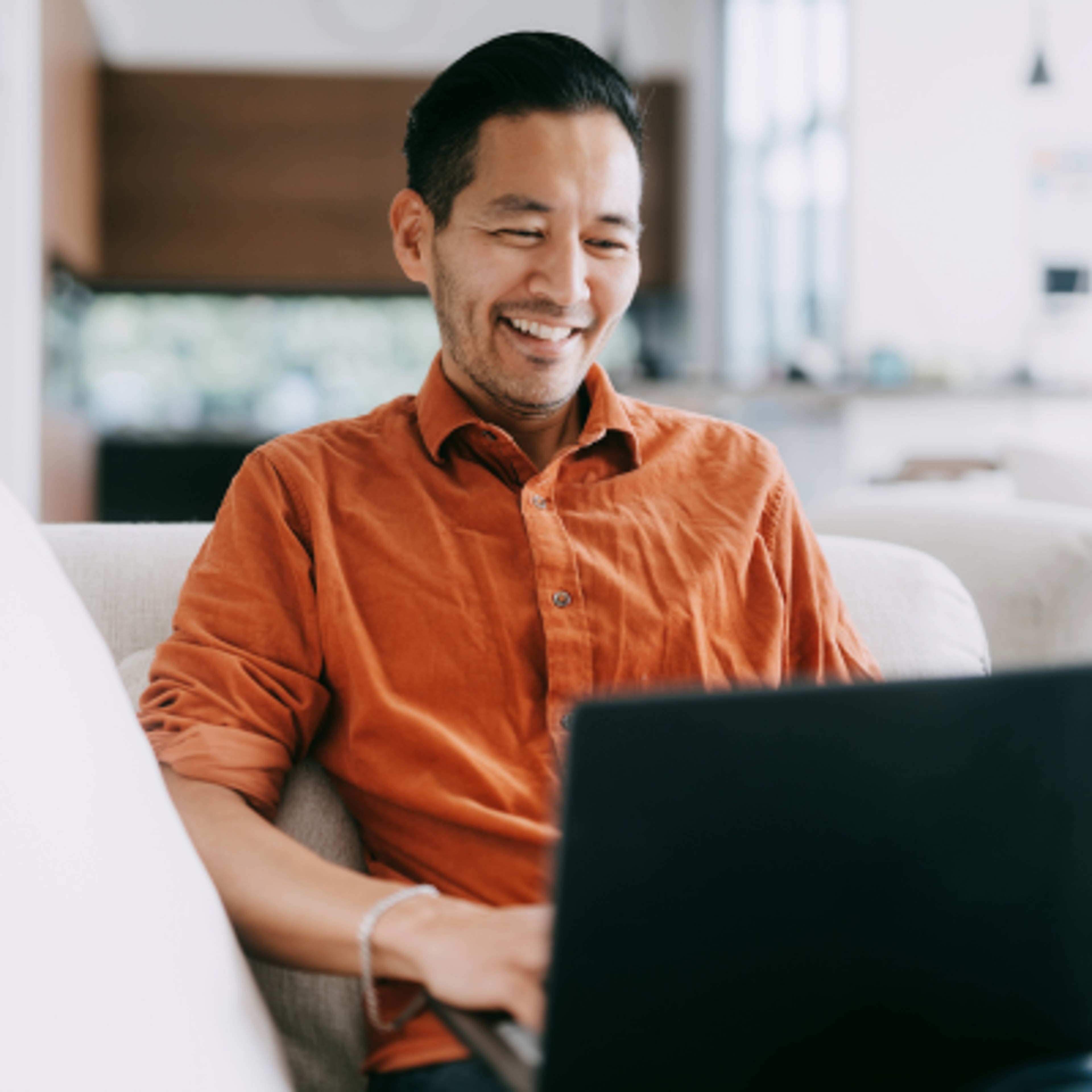A man sitting with Laptop in Orange Shirt