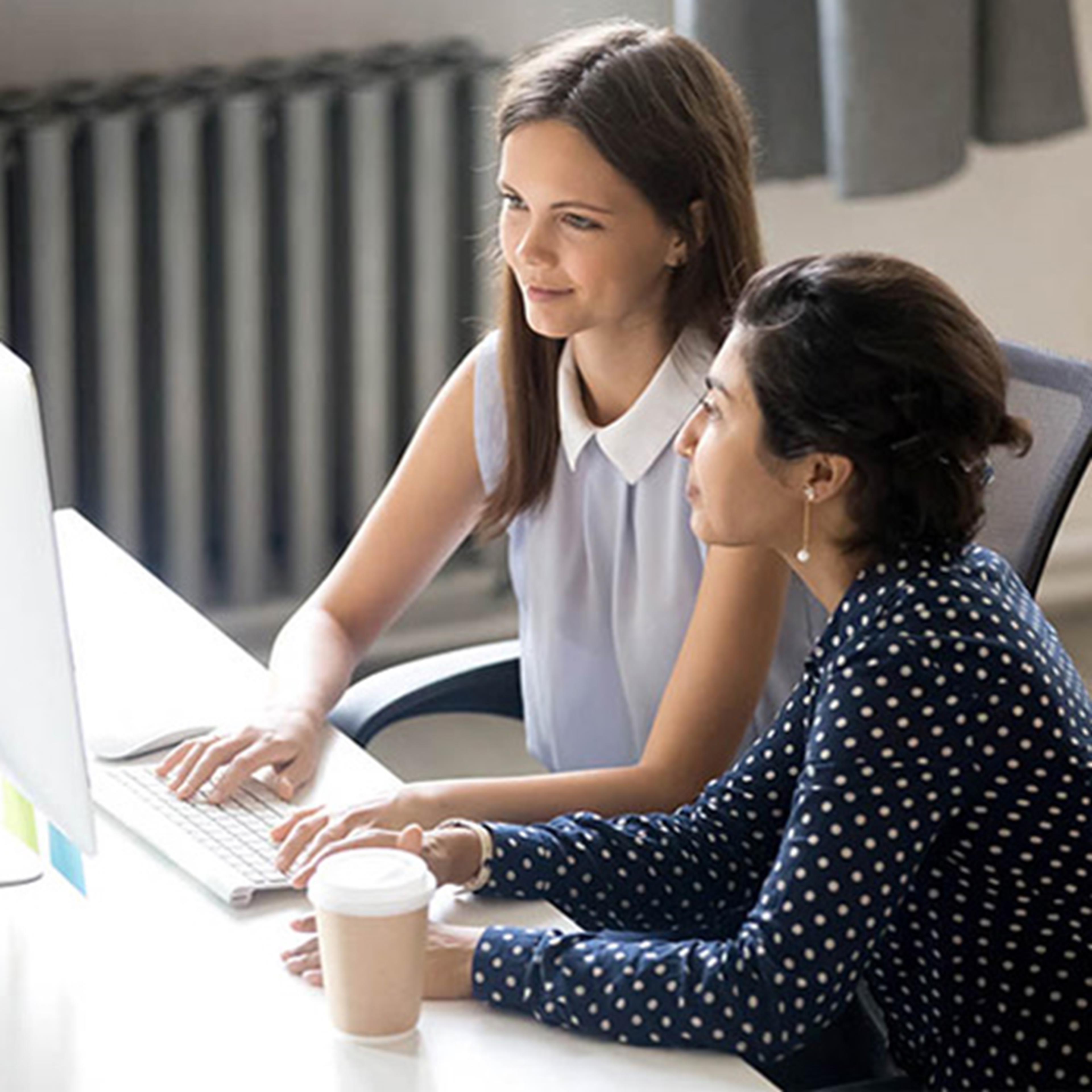 Two women working together in front of a desktop