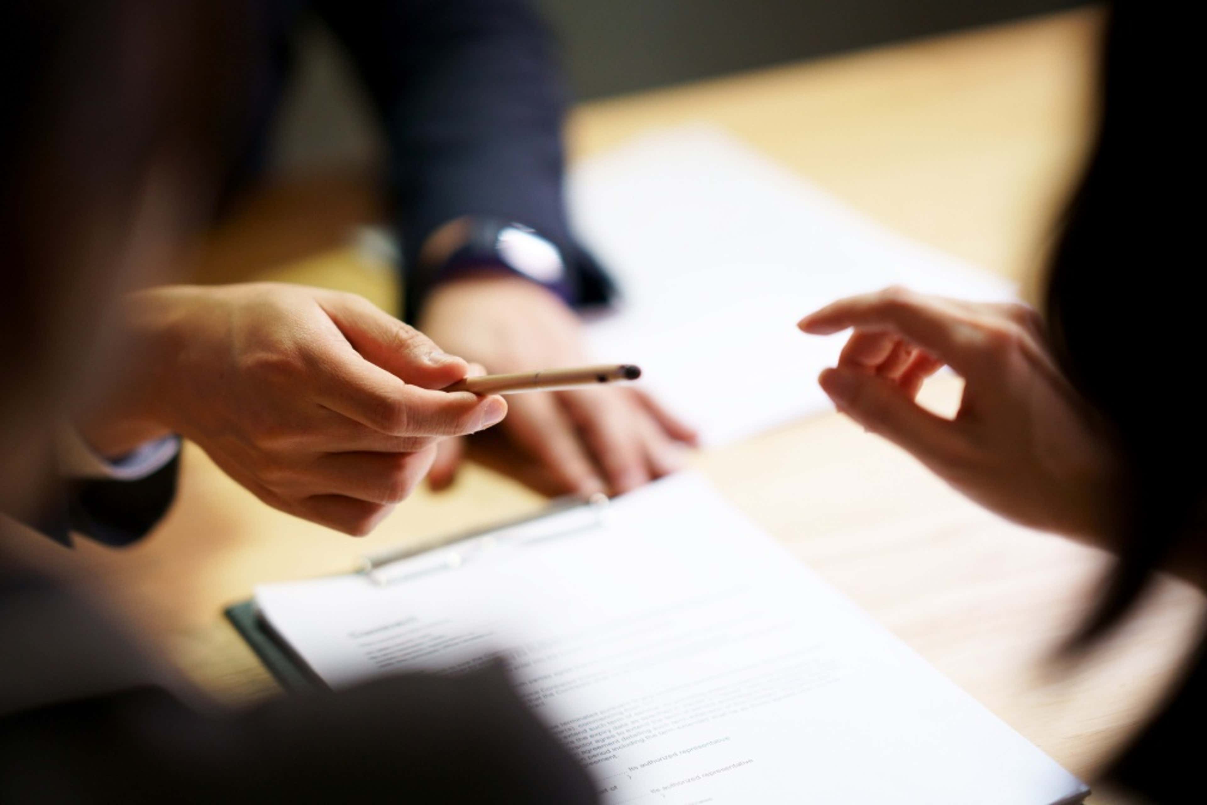 close up of a woman passing a pencil to another woman