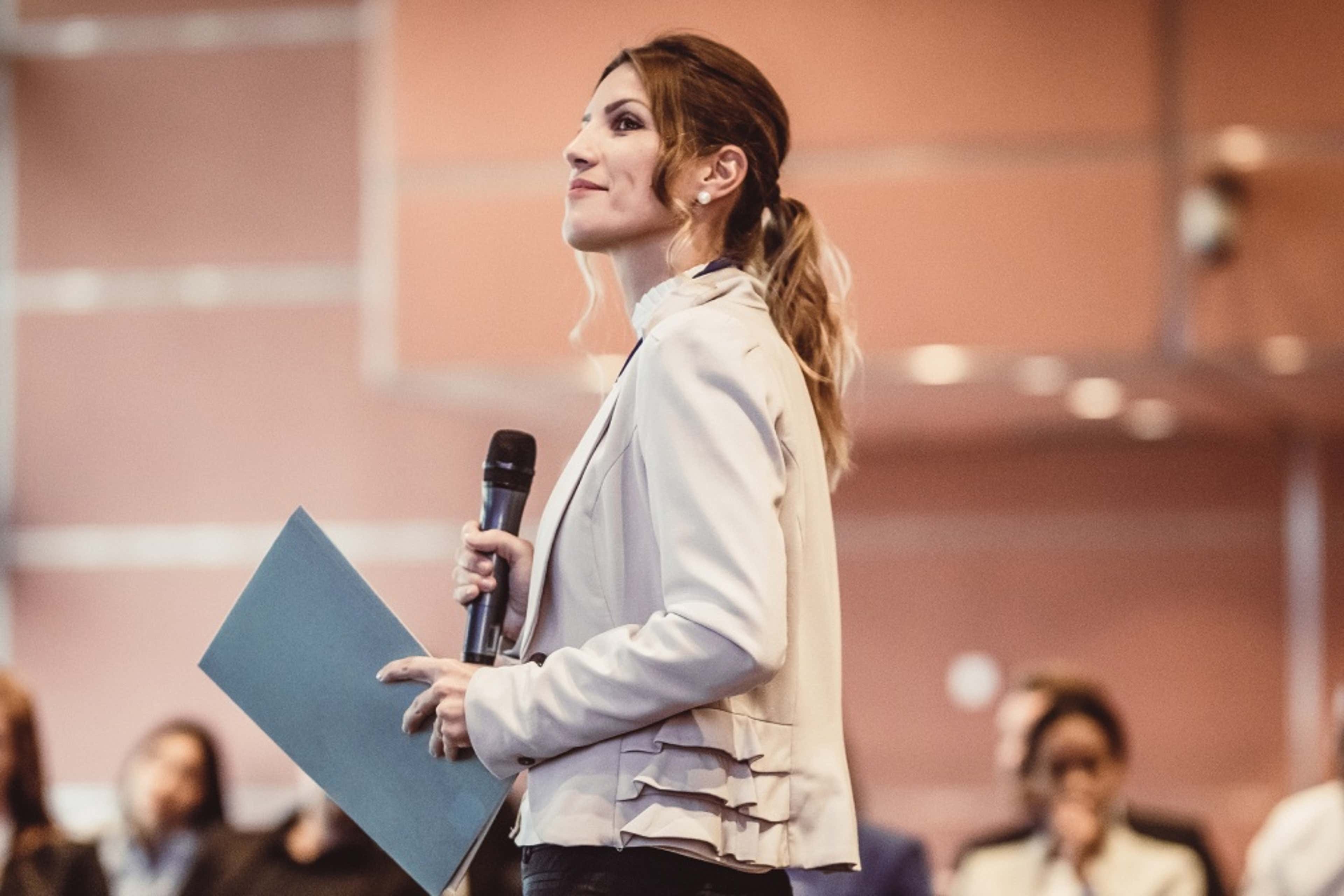 Woman in formal suit with a microphone 