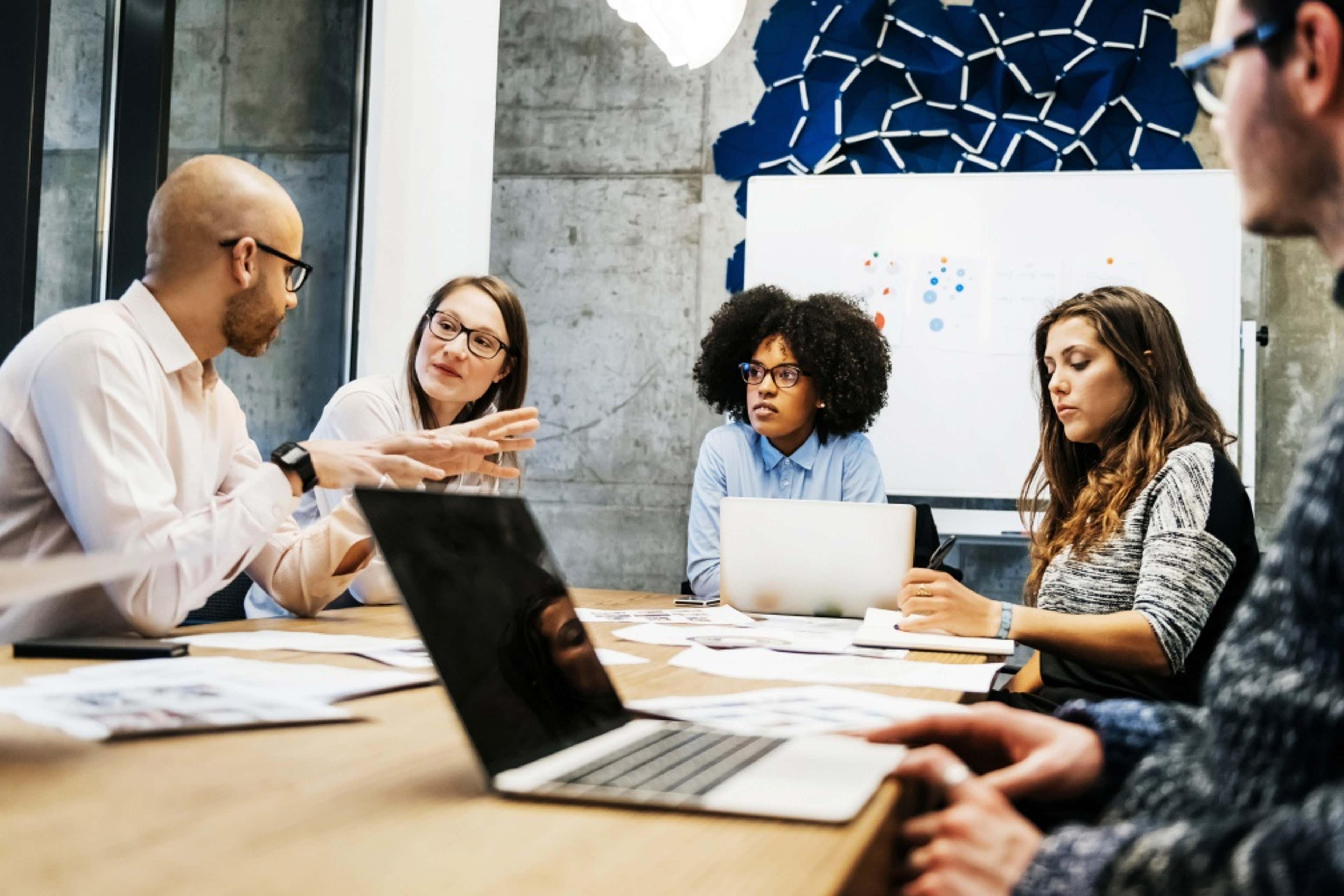 Group of people sitting with laptops, having a meeting inside a conference room 