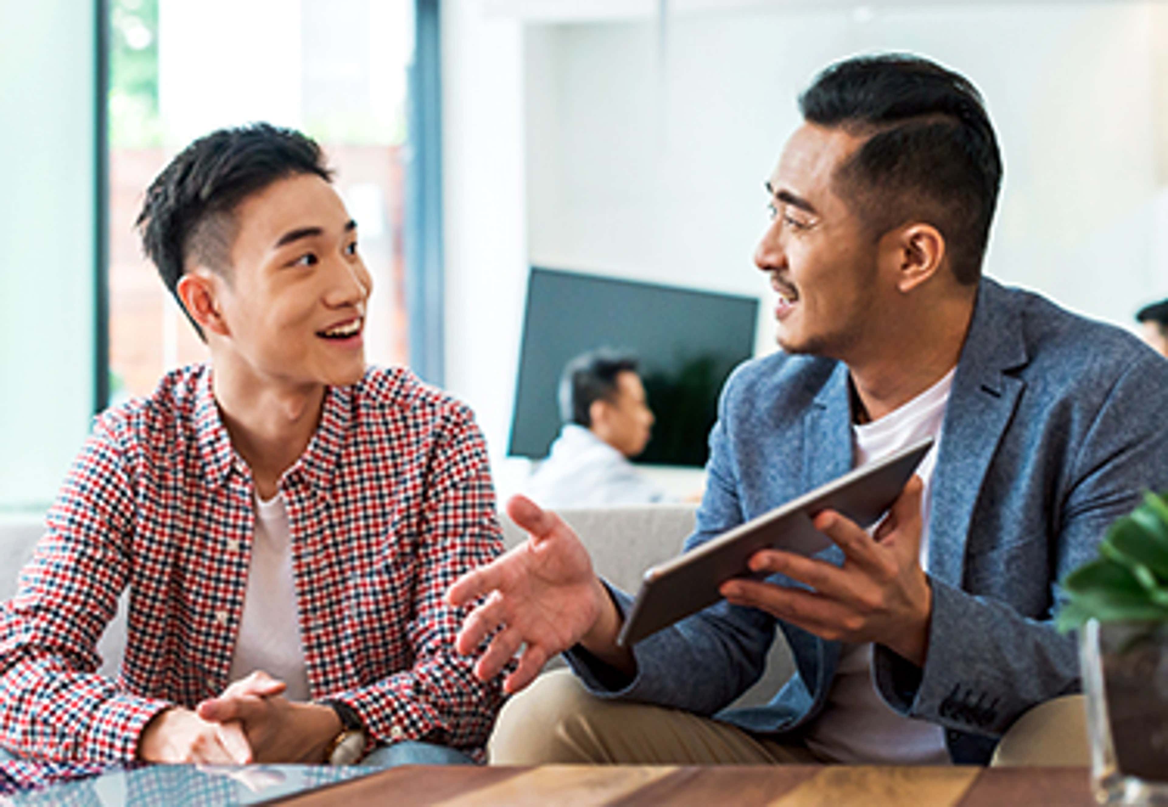 One man explaining to the other while showing a tablet