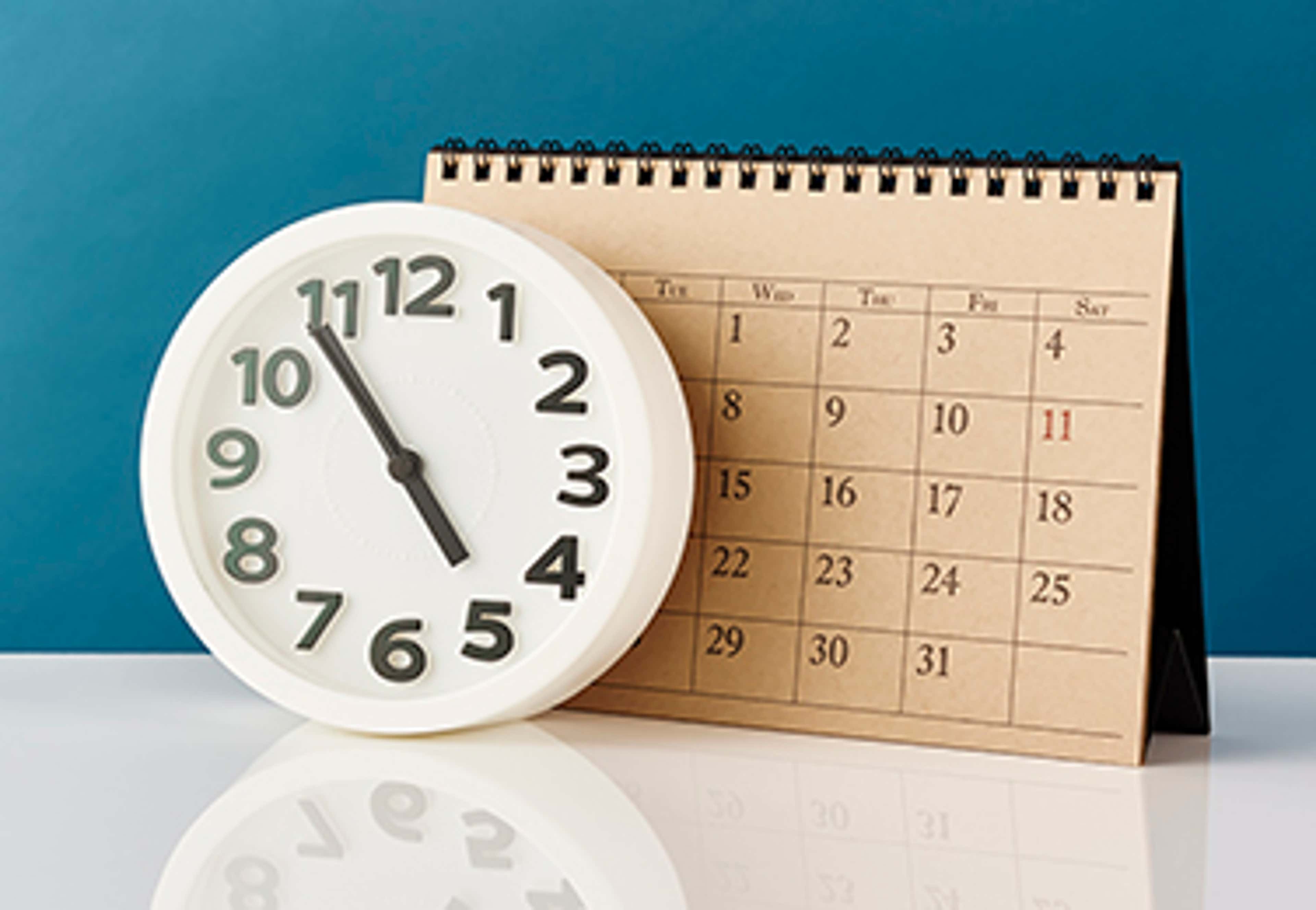 Calendar with analog clock in front of it