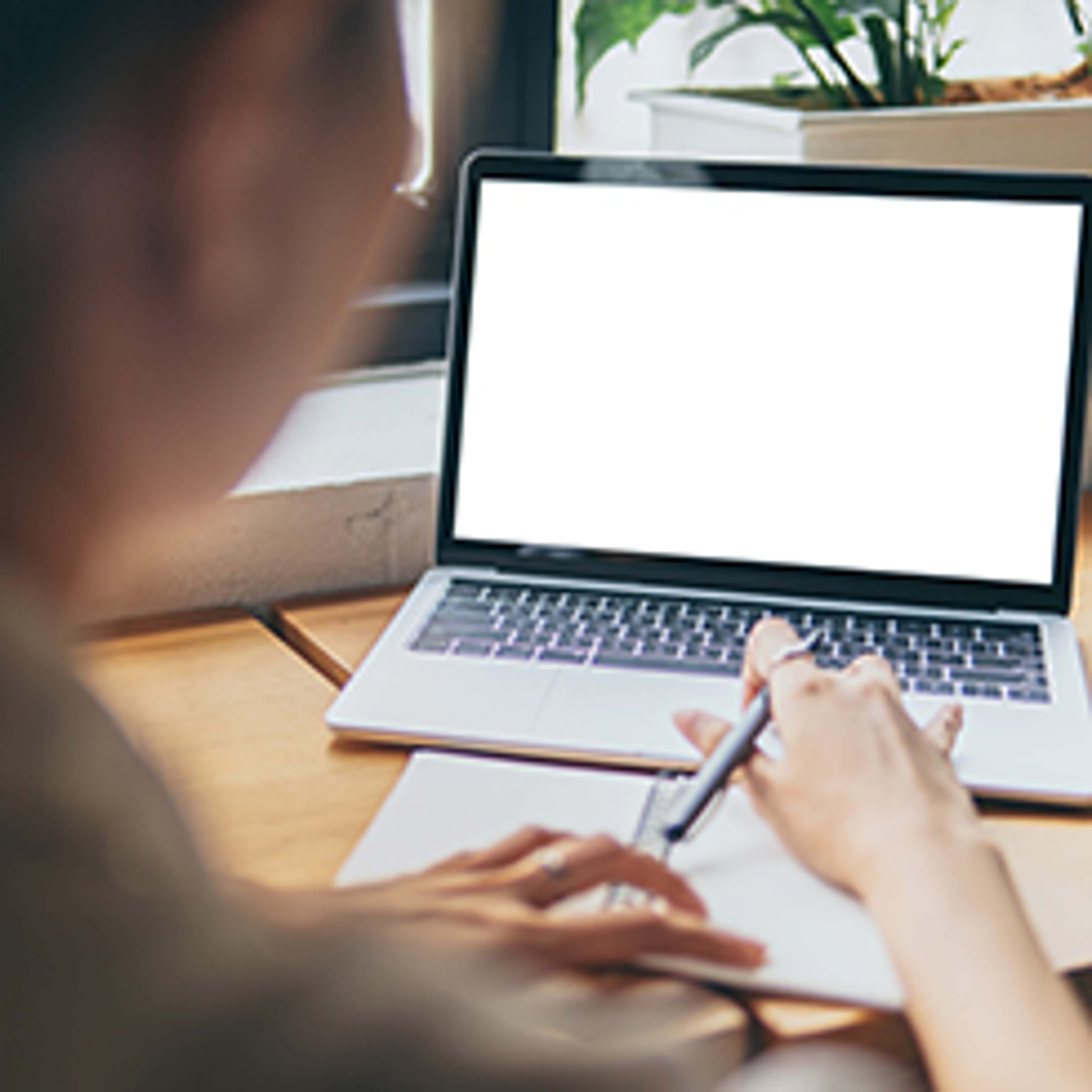 Student facing a laptop screen typing while holding a pen