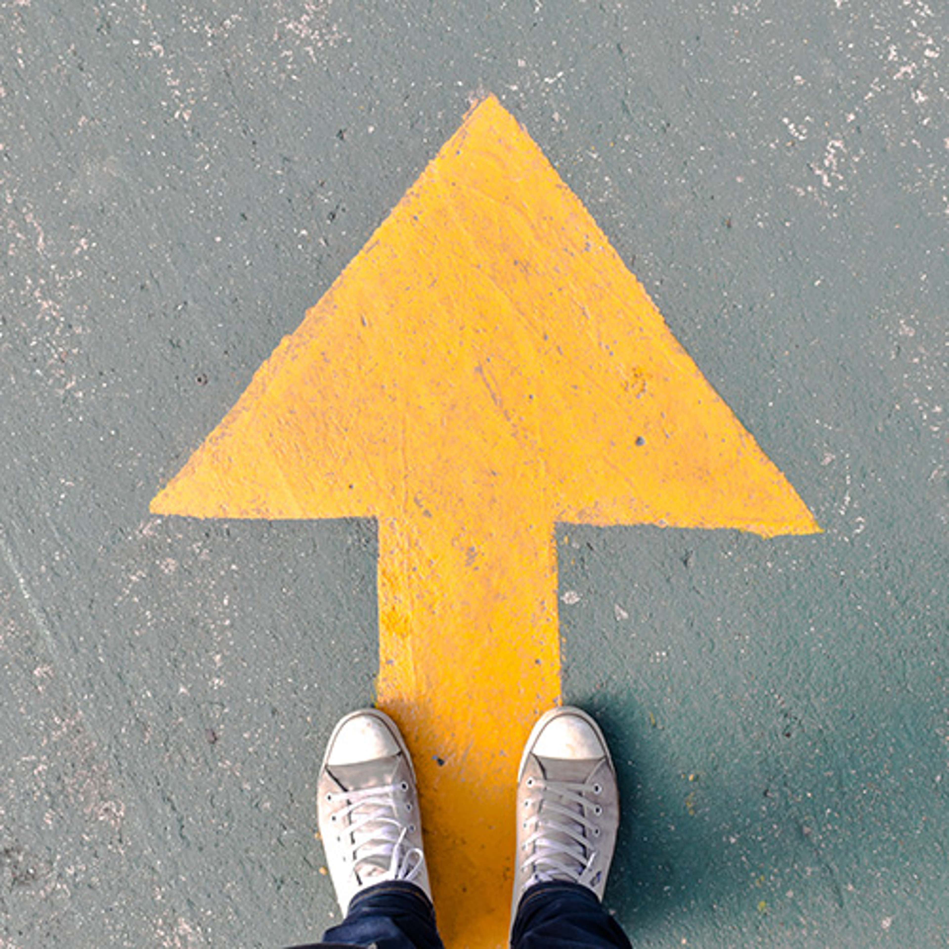 Yellow arrow on ground with feet at standing on it
